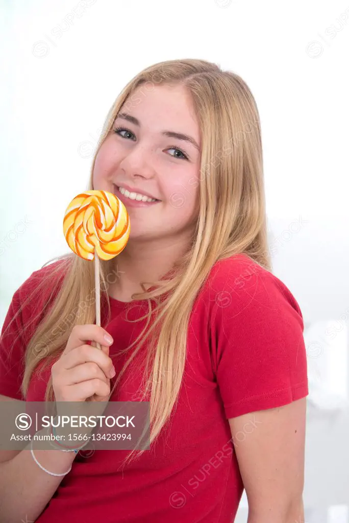 young school girl, 15 year old, in red, with a broad smile, holding a colorful lollipop