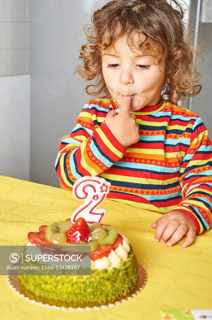 A two years old cacasian girl tasting her birthday cake.