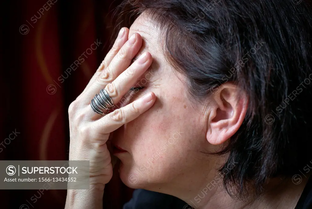 Middle-aged woman´s profile covering her face with her hand