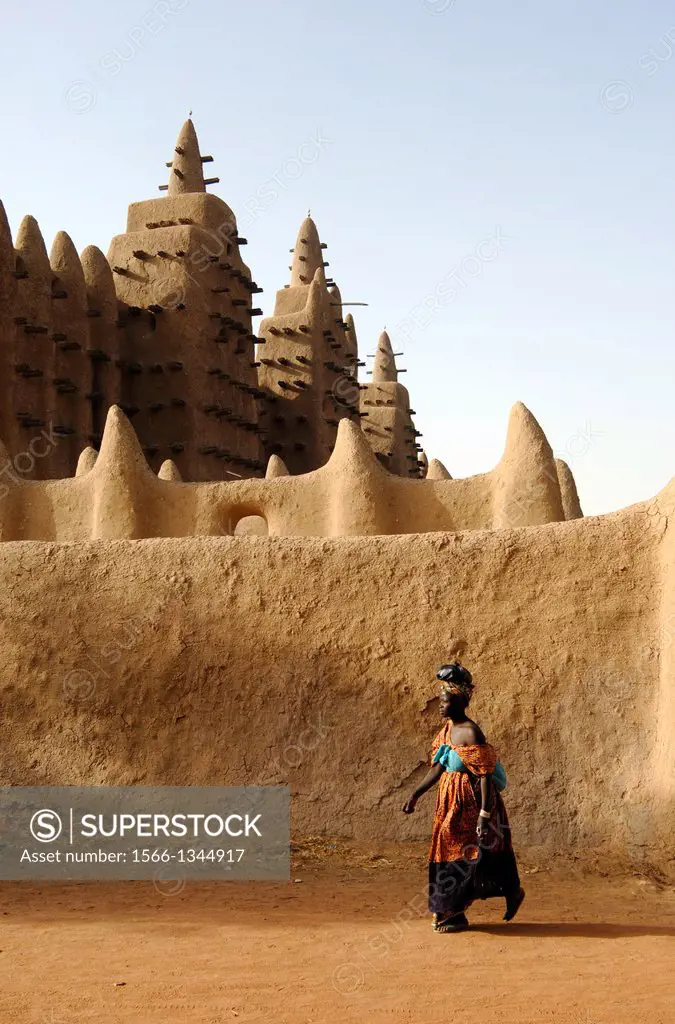 MALI, DJENNE, PEOPLE WALKING IN FRONT OF MOSQUE, MUD BRICK BUILDING, WORLD HERITAGE SITE.