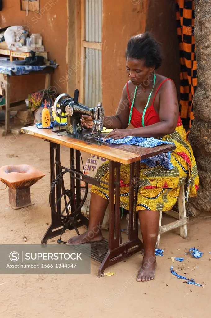 WEST AFRICA, TOGO, LOME, STREET SCENE, COURTYARD WITH WOMAN SEWING.