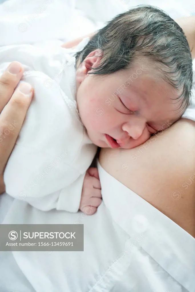 Newborn baby girl sleeping on her mother´s breast