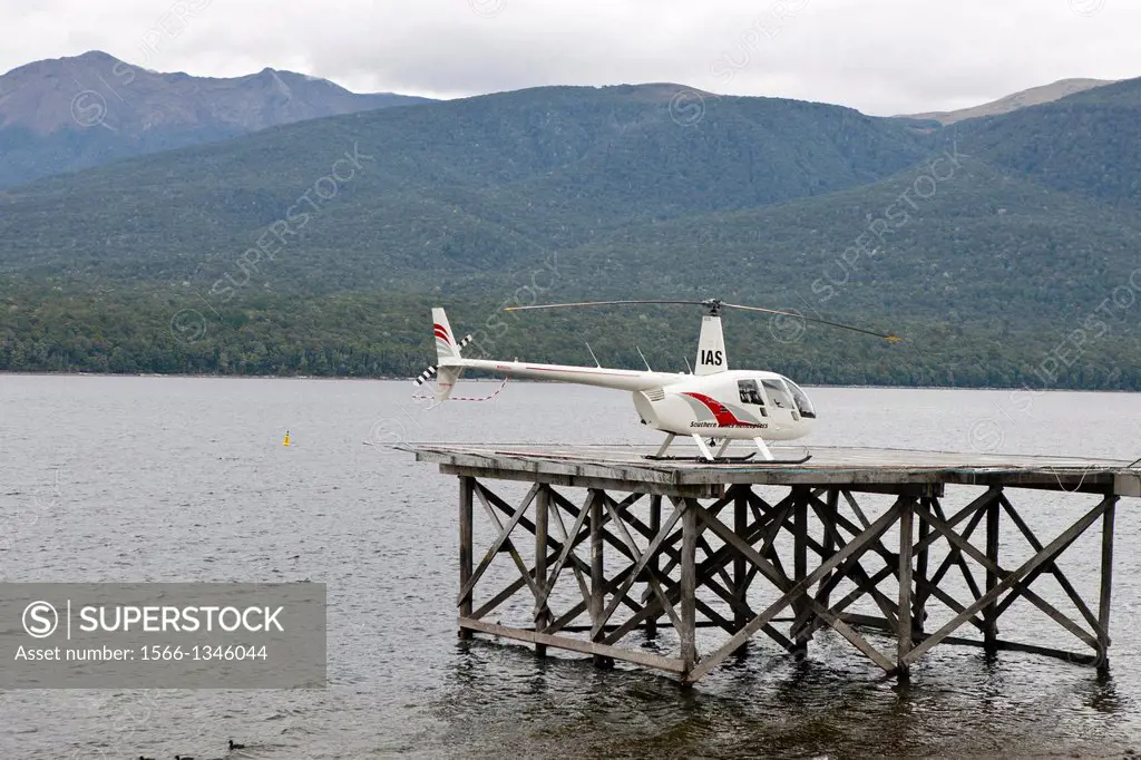 A helicopter sits on a dock with hills in the background, Lake Te Anau, South Island, New Zealand.