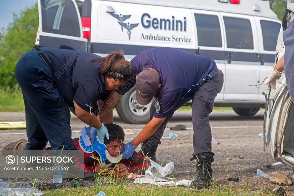 Falfurrias, Texas - EMTs treat a man injured when an van holding 26 undocumented immigrants from Central America overturned on Texas Highway 285. The ...