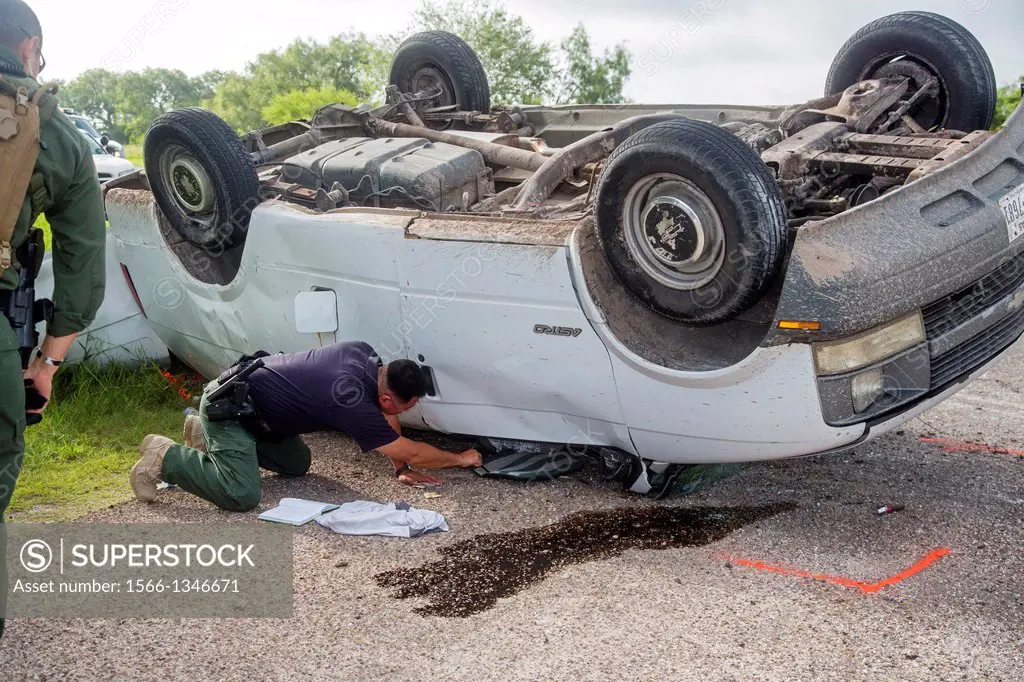 Falfurrias, Texas - A Border Patrol officer inspects a van holding 26 undocumented immigrants from Central America after it overturned on Texas Highwa...