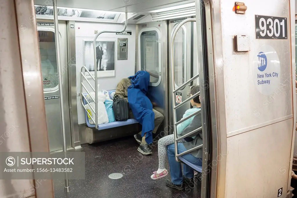 A homeless individual sleeps on the subway in New York