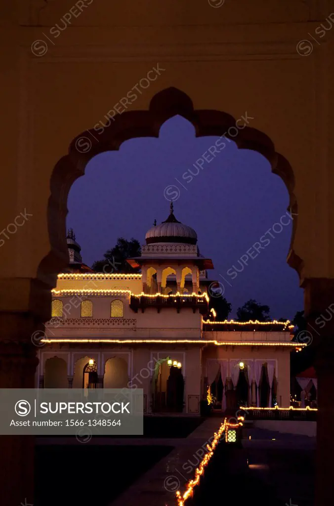 INDIA, JAIPUR, HOTEL RAMBAGH PALACE, A FORMER PALACE OF THE MAHARAJAS OF JAIPUR, AT NIGHT.