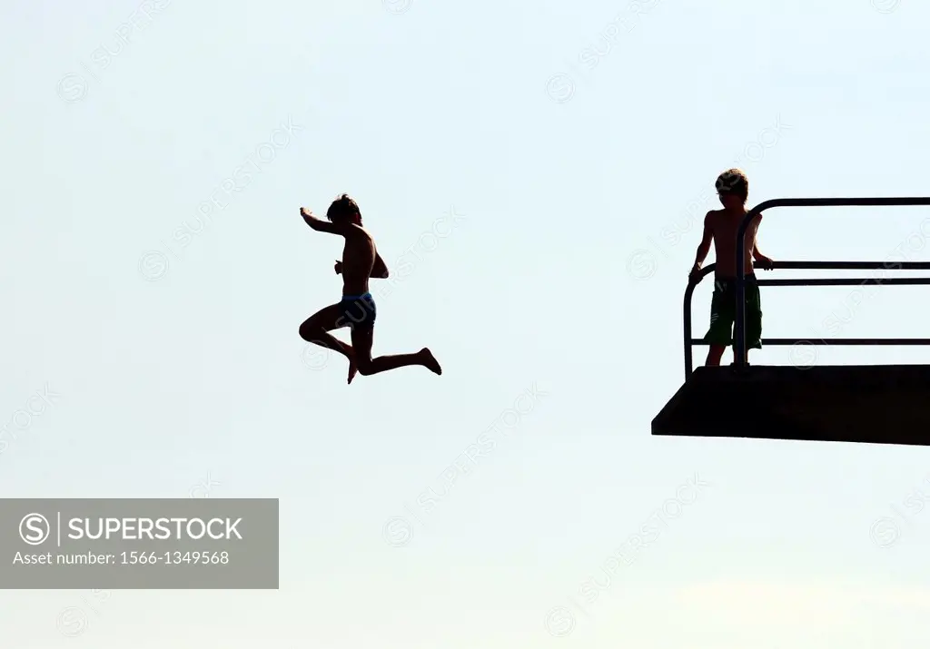 single teenager jumping from diving tower to waters of Lake Geneva, Paquis beach, Geneva, Switzerland
