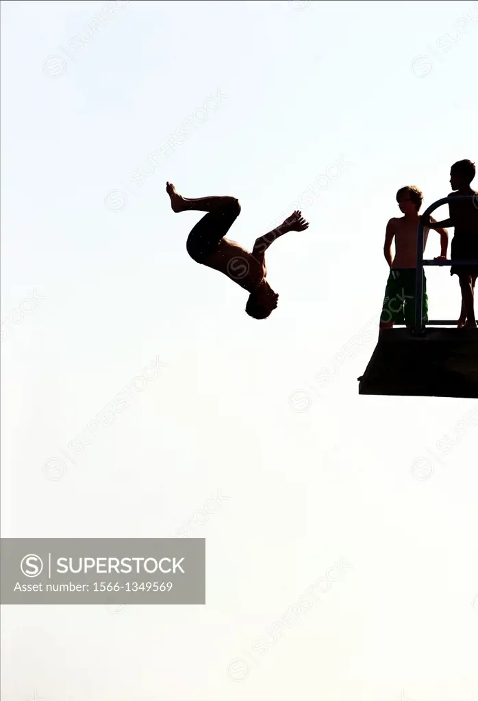 single man jumping from diving tower to waters of Lake Geneva, head first, Paquis beach, Geneva, Switzerland