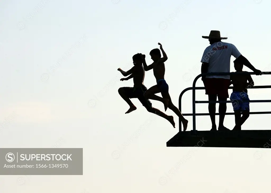 two teenagers jumping together from diving tower to waters of Lake Geneva, Paquis beach, Geneva, Switzerland