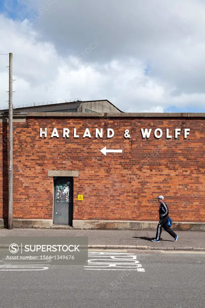 Sign at Dee Street entrance to Harland and Wolff Shipyard, Belfast, Northern Ireland with a male walking past.