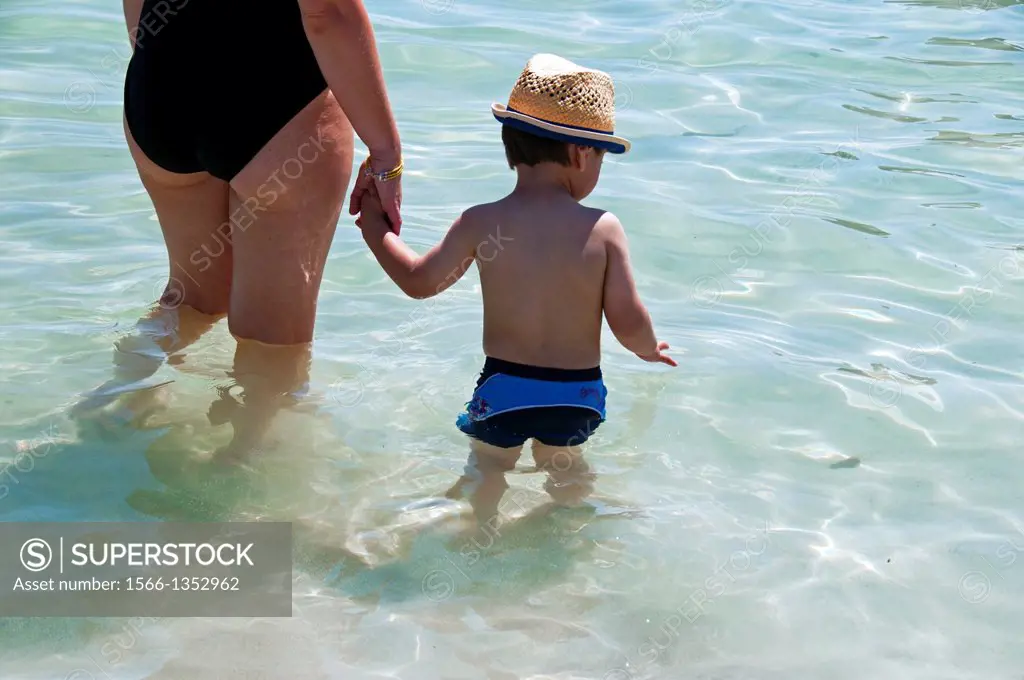 woman holding hand of a little boy in the water of the sea, Playa Muro, Mallorca, Majorca, Balearic Islands, Spain, Europe