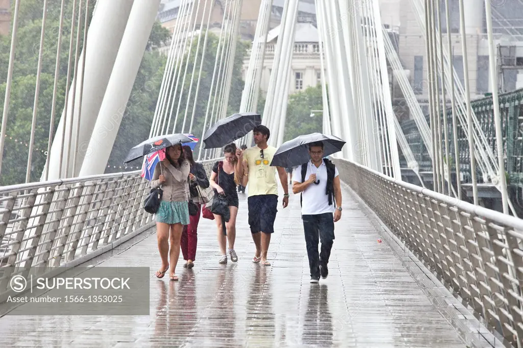 Tourists Crossing The Golden Jubilee Footbridge In The Rain, London, England.