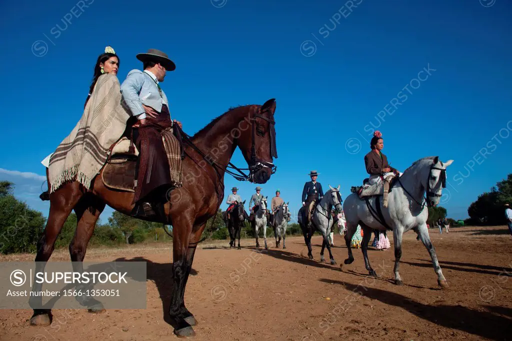 Riders pass a couple riding a horse after crossing the Guadiamar´s river ford, known as Vado del Quema, during the pilgrimage to the shrine of the Vir...