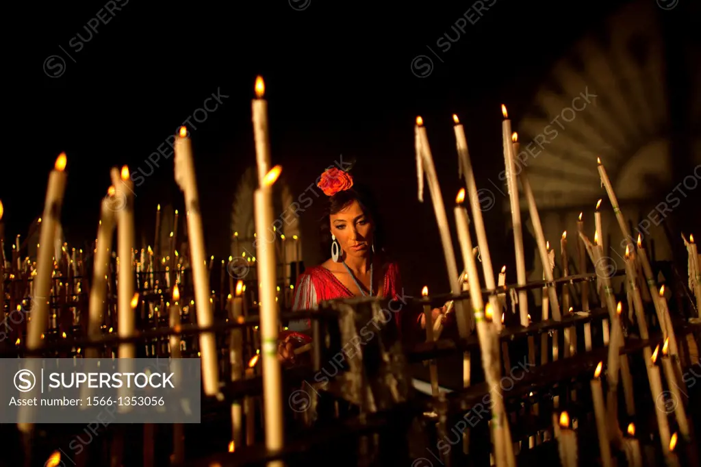 A woman lights a candle in the Votive Room of the shrine of the Virgin of Rocio, in Almonte, Donana National Park, Huelva province, Andalusia, Spain, ...