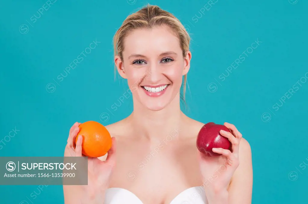Beautiful woman holding apple and orange smiling.