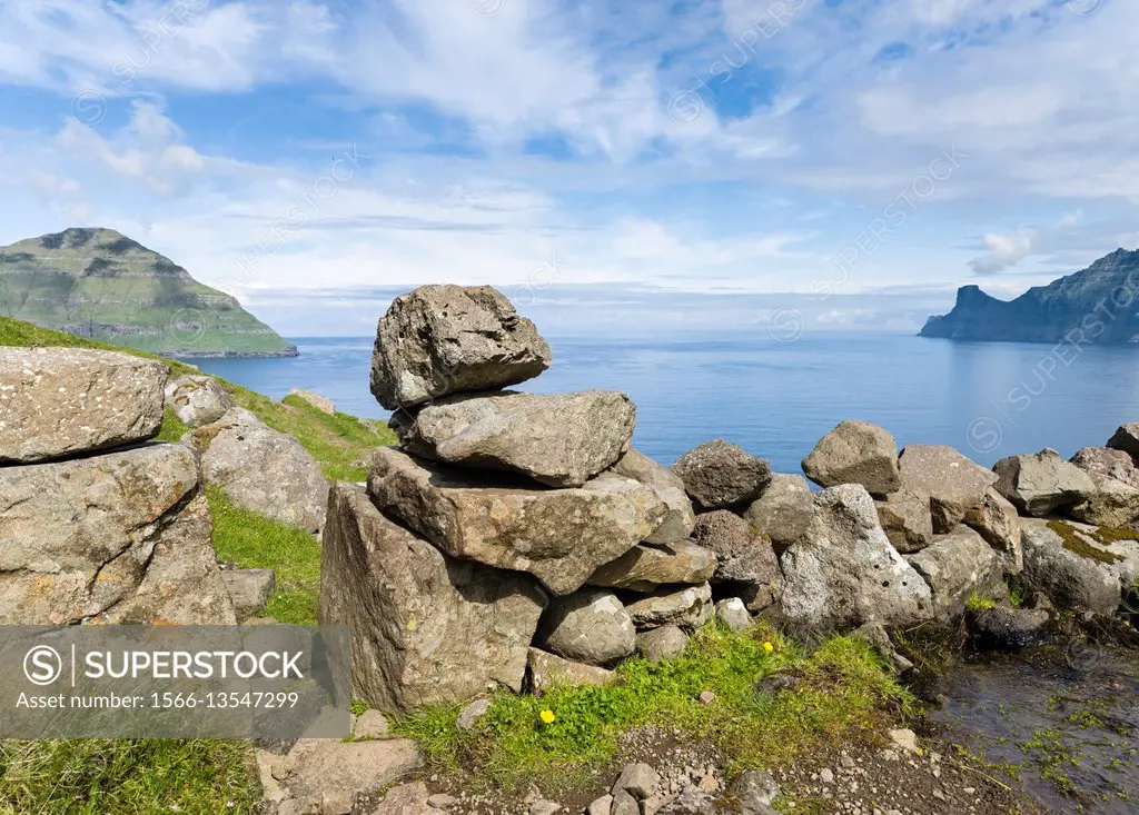 Old dry stone wall, view towards Kalsoy and fjord Leirviksfjord. Village Oyndarfjordur, in the background the mountains of the island Kalsoy. The isla...