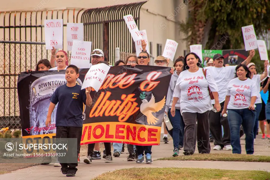 Local Hispanics march in Santa Ana, CA, to a rally against street violence in the community. Note banner with sign. Note T shirts.