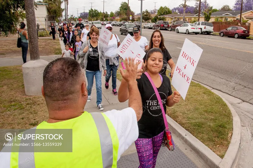Local Hispanics high five a parade monitor in Santa Ana, CA, as they arrive at a rally against street violence in the community. Note T shirts with an...