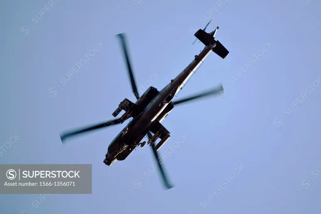 Military helicopter photographed from below showing the rotary blades motion stopped.