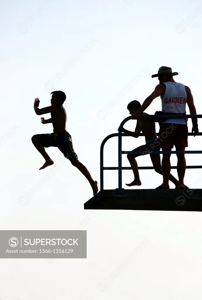 two teenagers jumping from diving tower to waters of Lake Geneva, Paquis beach, Geneva, Switzerland