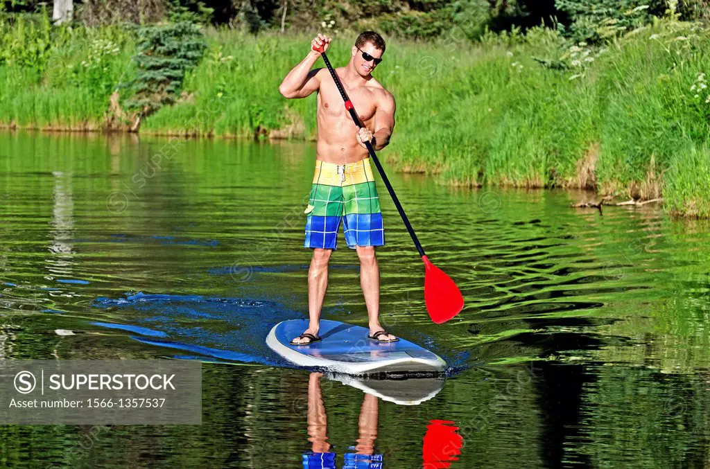 Riding the Stand Up Paddle Board on the North Fork of the Payette River near Payette Lake and the city of McCall in the Salmon River Mountains of cent...