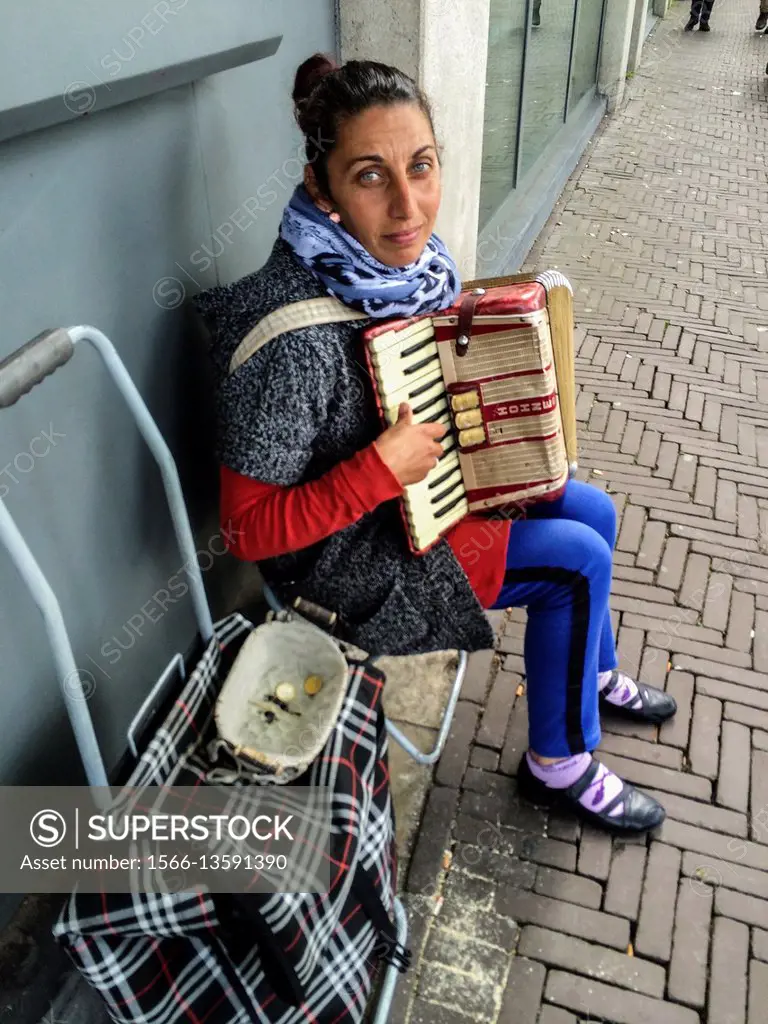 The Hague, Netherlands. Middel aged and eastern European woman playing the harmonica in the streets for a dime or two a day.