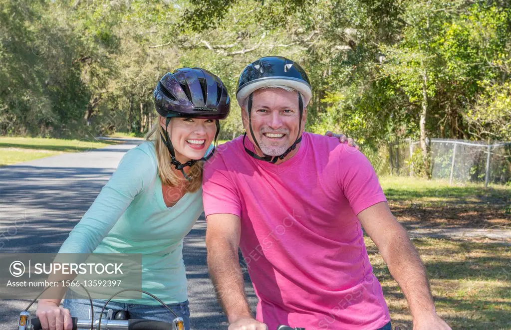 couple aged 40s and 50s riding bike at home in neighborhood safety helmets exercise healthy lifestyle care love Model Released, MR-5, MR-6.