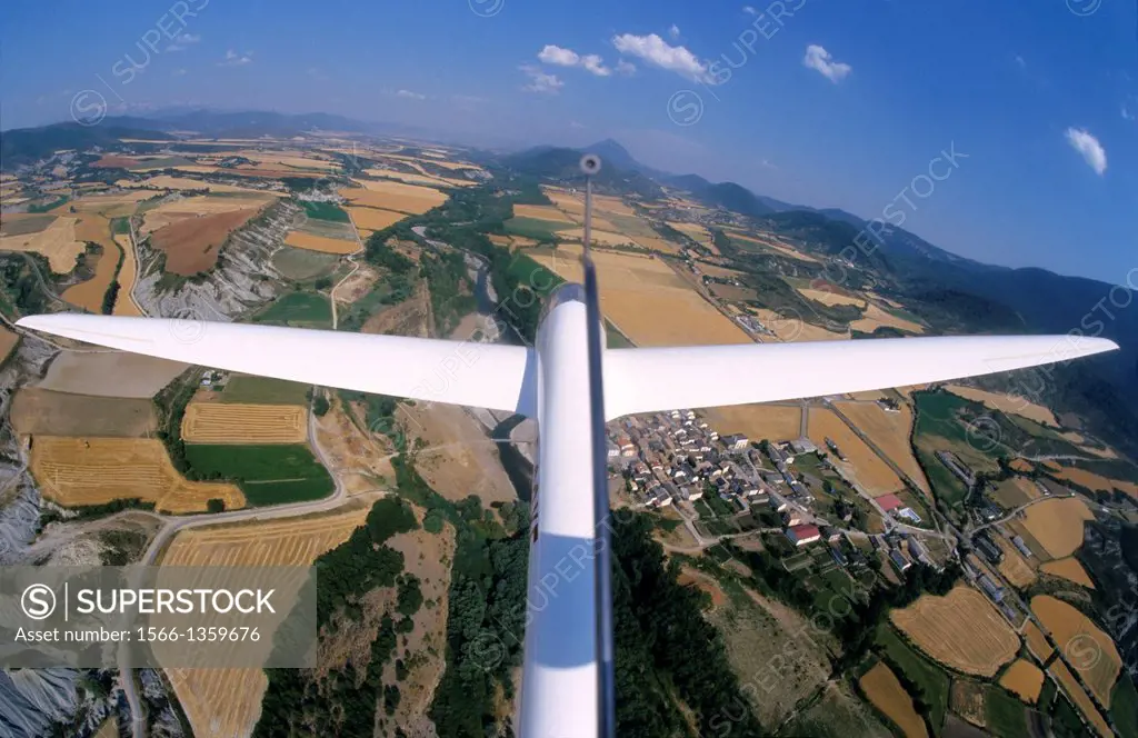 Glider plane Twin Astir flying over Santa Cilia de Jaca village and Rio Aragon river, Aragon, Spain