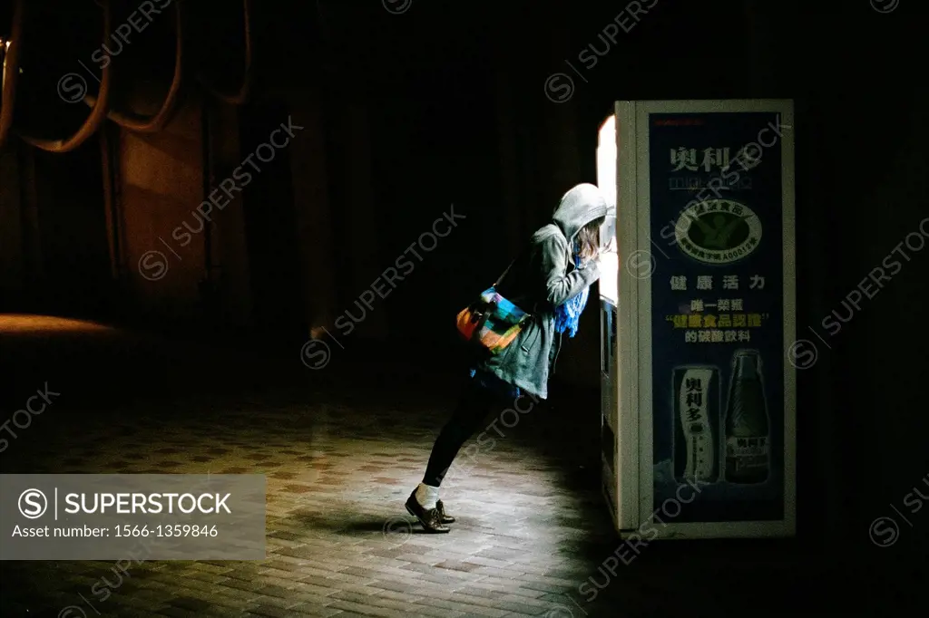 A girl leans on a vending machine at night in Kaohsiung, Taiwan