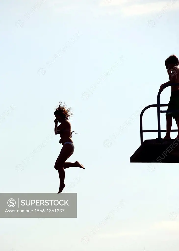 Single woman jumping from diving platform to waters of Geneva Lake, Paquis beach, Geneva, Switzerland