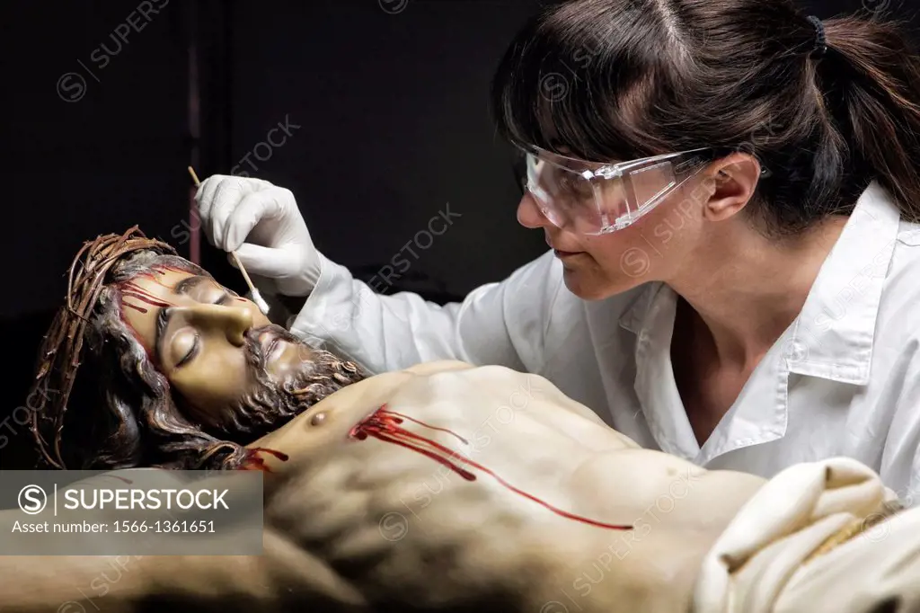 Cleaning of the face of a wooden sculpture of Christ crucified with an isopo impregnated with dimethylformamide, Andalusia, Spain.
