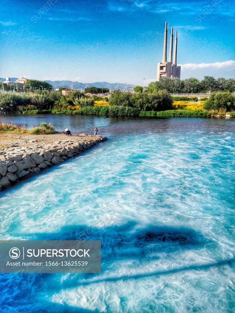 Besos river, purified water from treatment plant, in the background the chimneys of the old thermal power station, Sant Adrià del Besòs, Barcelona, ...