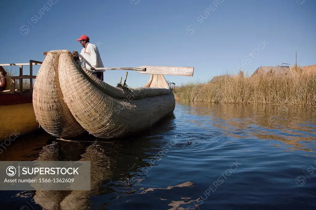 Aymara indigenous man on a reed boat at the Uros Islands, Lake Titicaca, Peru, South America.