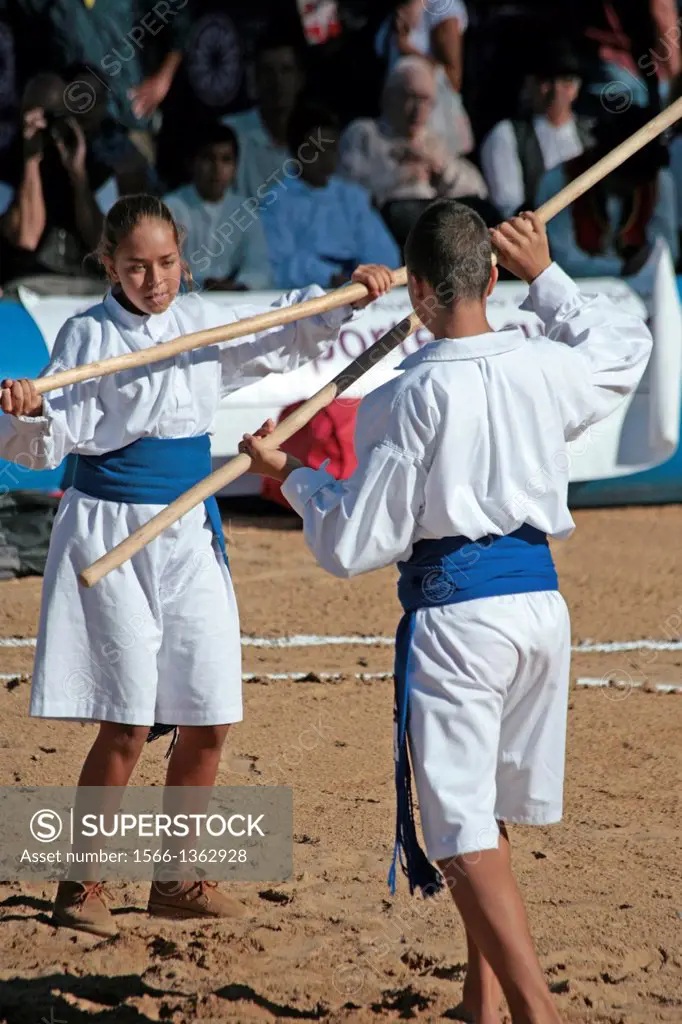 Teens playing the canarian stick fighting in a public exhibition in the open air