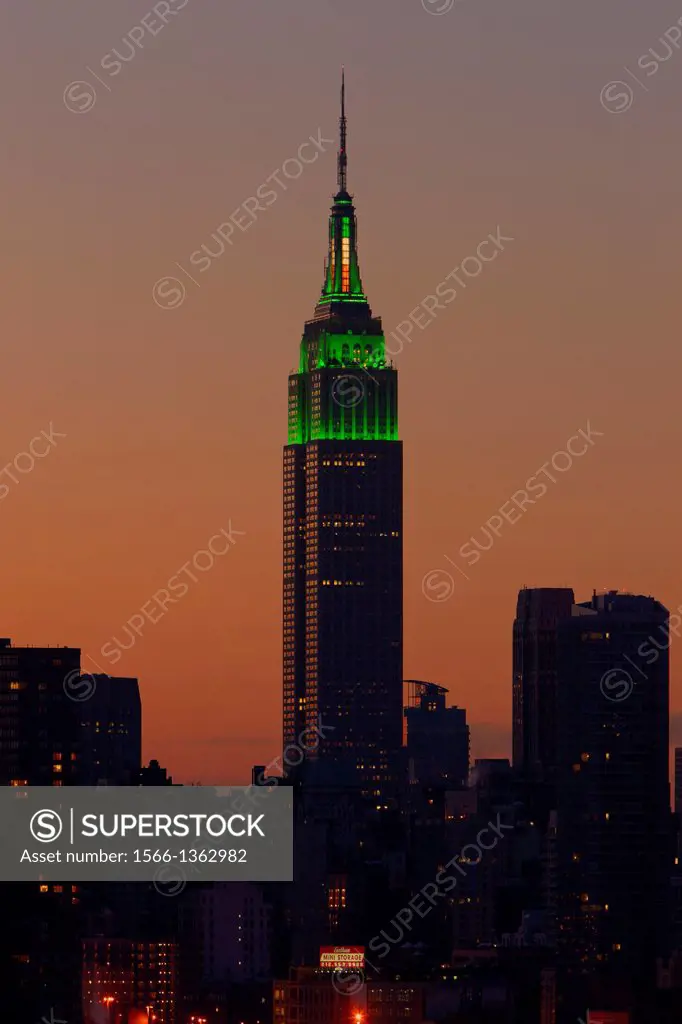 NEW YORK - MARCH 17: The Empire State Building is illuminated in green lights in celebration of St. Patrick's day as the sky glows orange before sunri...