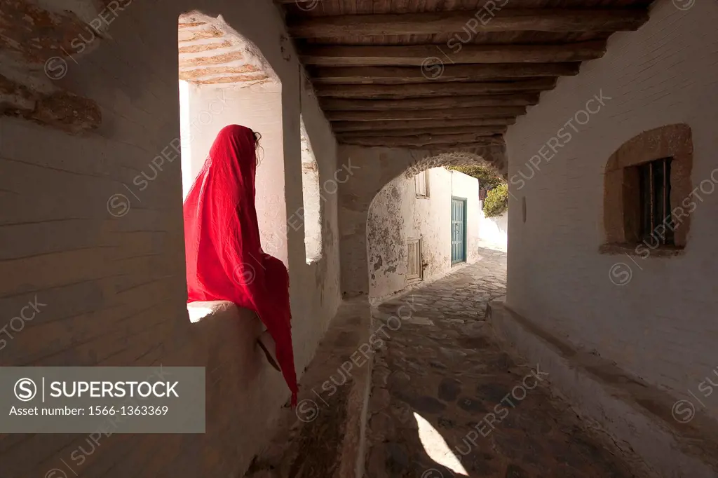 Woman sitting in the alley of Amorgos town, Amorgos, Cyclades Islands, Greek Islands, Greece, Europe.