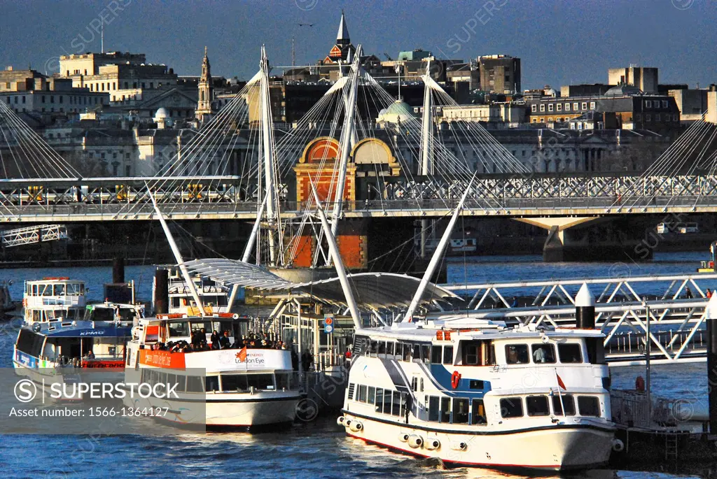Thames cruising boats at the London Eye Pier, in the heart of London, England,, on the River Thames, on a very sunny day, with Hungerford Bridge in th...