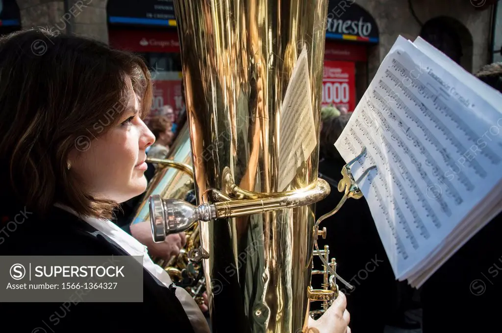 A woman playing the tuba in the marching band during a parade through the streets of Llanes. Asturias.Spain.
