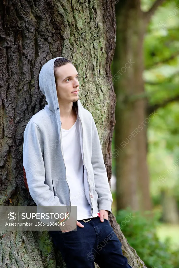 Young man standing by himself and thinking in a forest.