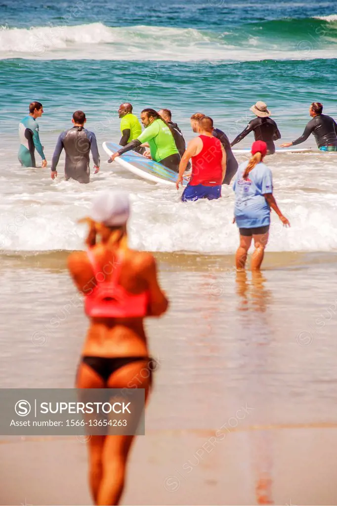 In thanks for his military service, a veteran receives a free surfing lesson from a female instructor (left) as they wade into the Pacific Ocean in Hu...