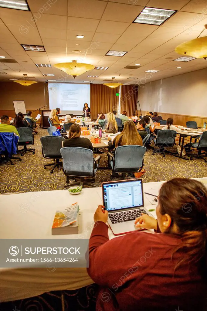 At a Los Angeles seminar for schoolteachers, a student follows along with the lecturer using a laptop computer. Note computer image on lecture screen.