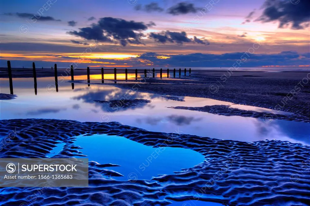 beach and wooden groyne at sunset, with large pools of water and cloud reflections, blackpool, lancashire, england, uk,europe.