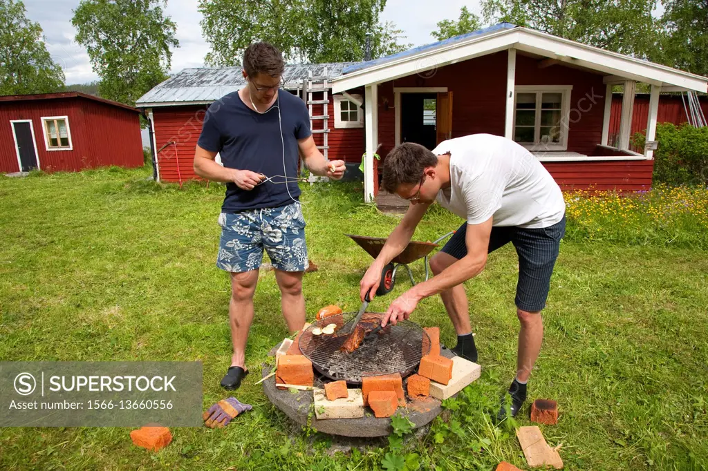 Brothers grilling meat, countryside of northern Sweden.