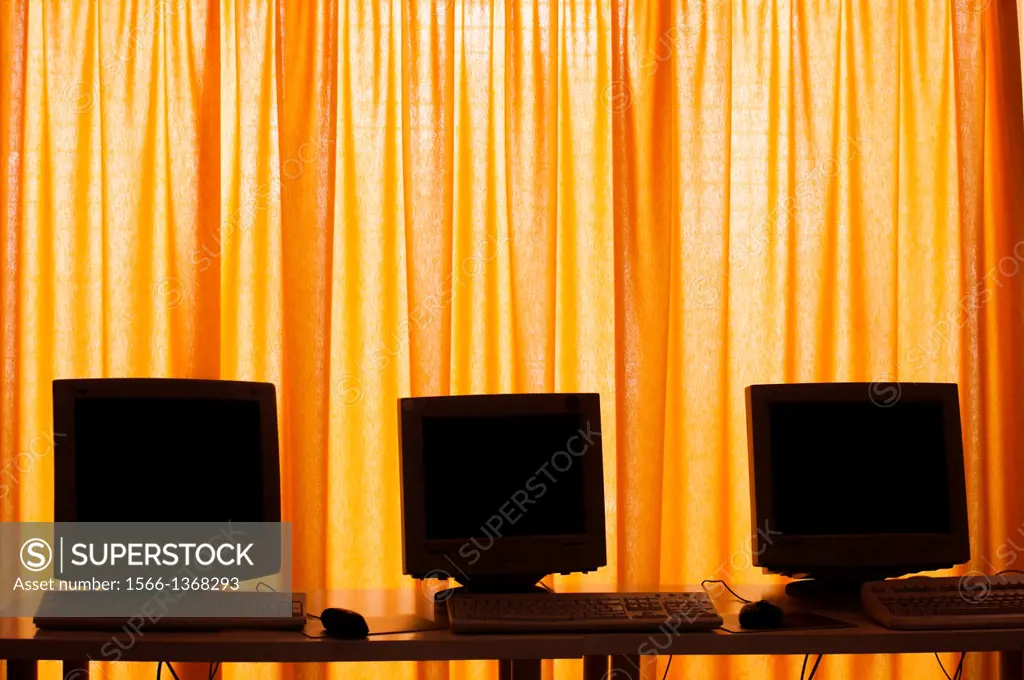 three computer screens on yellow curtains.