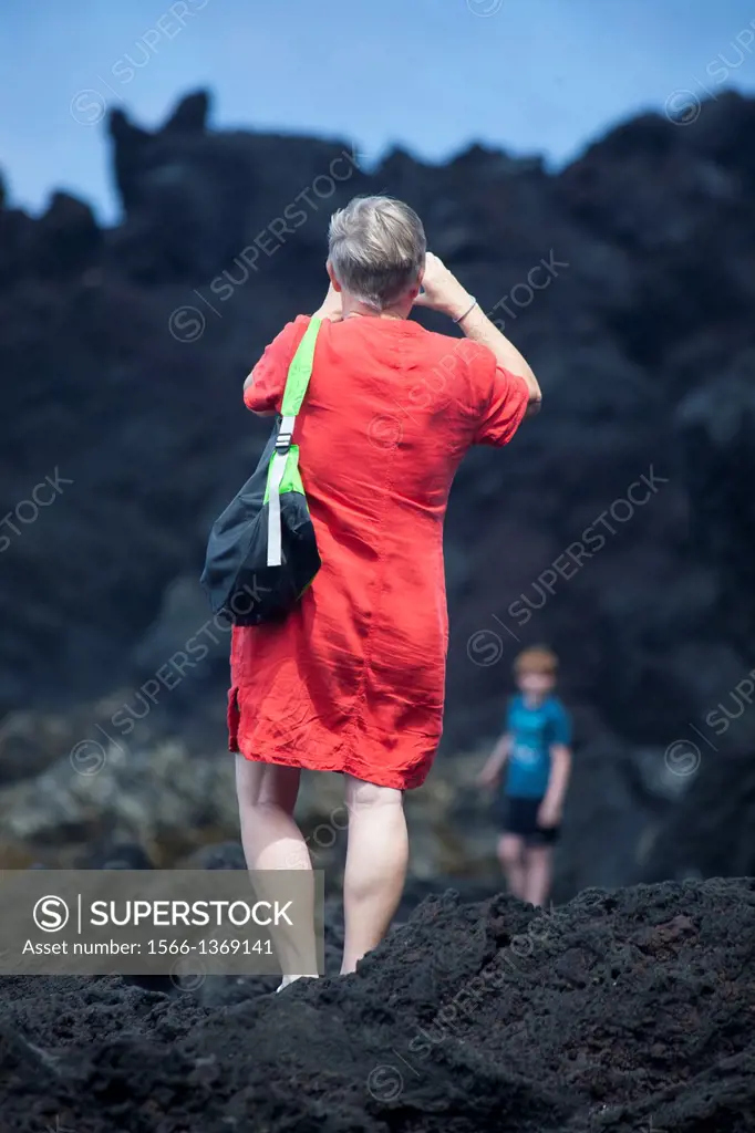 Woman taking a picture in the coast. Sao Miguel Island, Azores, Portugal.