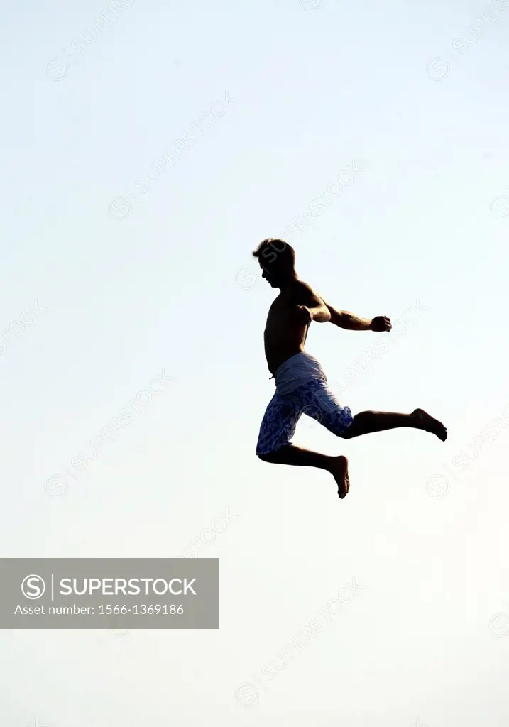 Silhouette of single man in the air, actually man is jumping from diving tower to waters of Lake Geneva, Paquis beach, Geneva, Switzerland
