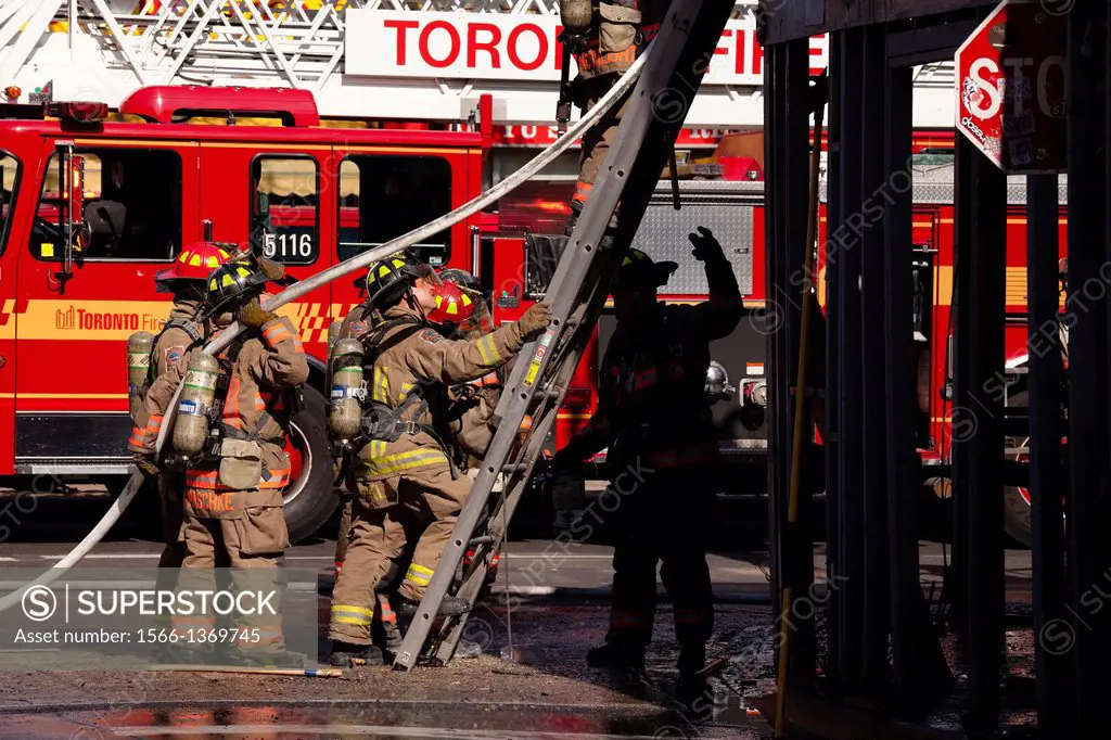 Firefighters at the base of a ladder during a fire in Kensington Market, Toronto, Ontario, Canada.