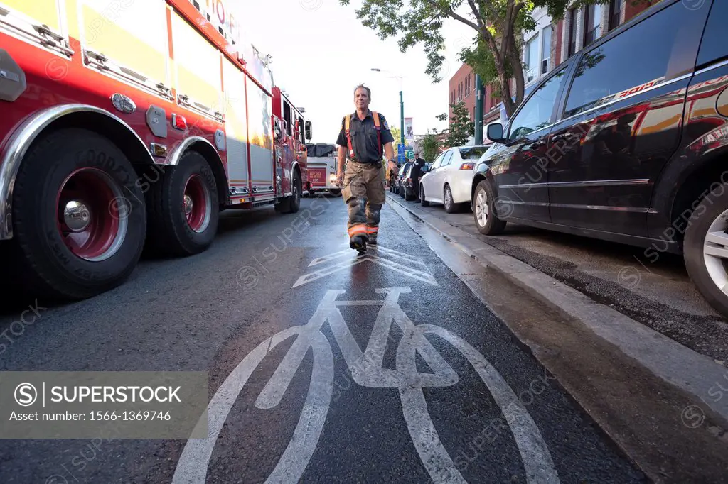 A firefighter walking towards a bike lane marking during a fire in Kensington Market, Toronto, Ontario, Canada.