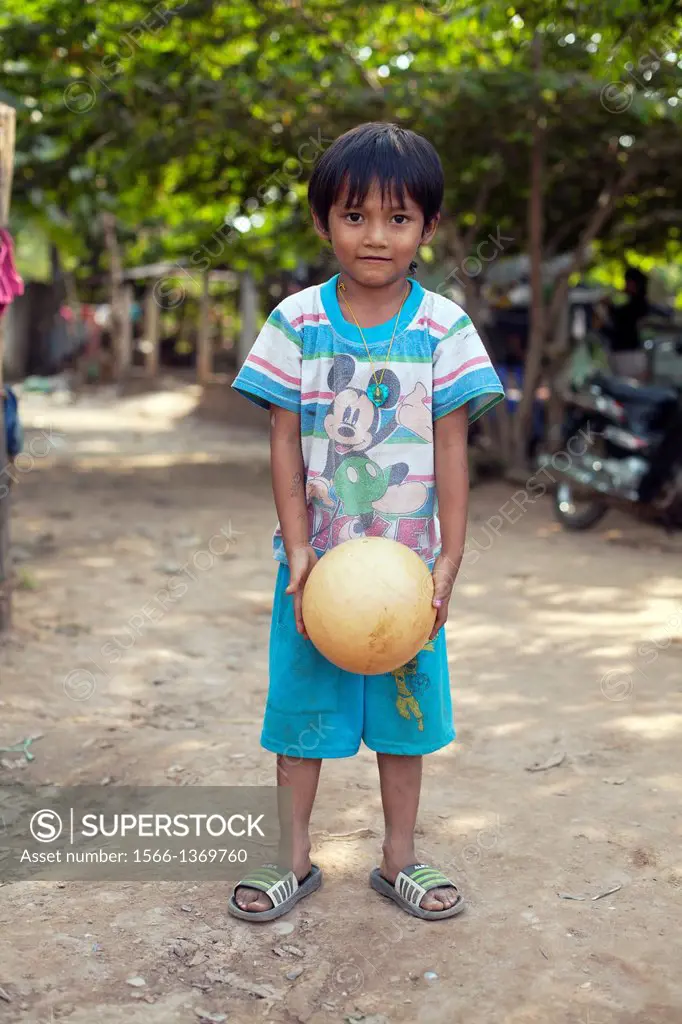 Portrait of a young boy with a ball in a small village outside of Phnom Penh, Cambodia.